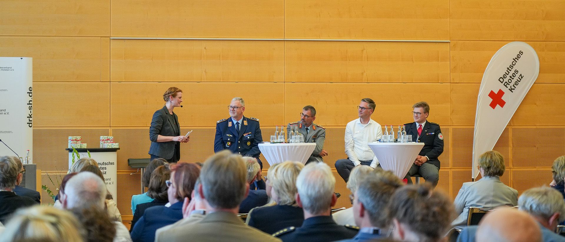 Fünf Menschen diskutieren auf einer Bühne vor großem Publikum im Vordergrund.