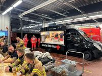 Etwa ein Dutzend Einsatzkräfte stärkt sich an einem Imbisswagen des Deutschen Roten Kreuzes.