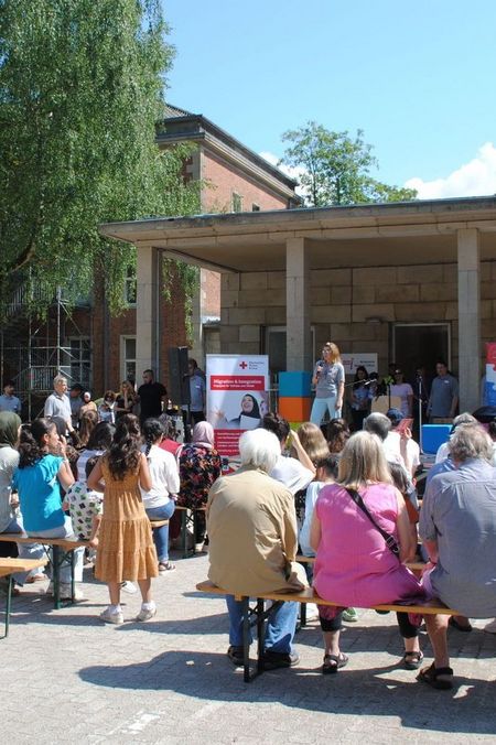 Eine Person steht auf einer Bühne und spricht zu rund 50 Leuten.