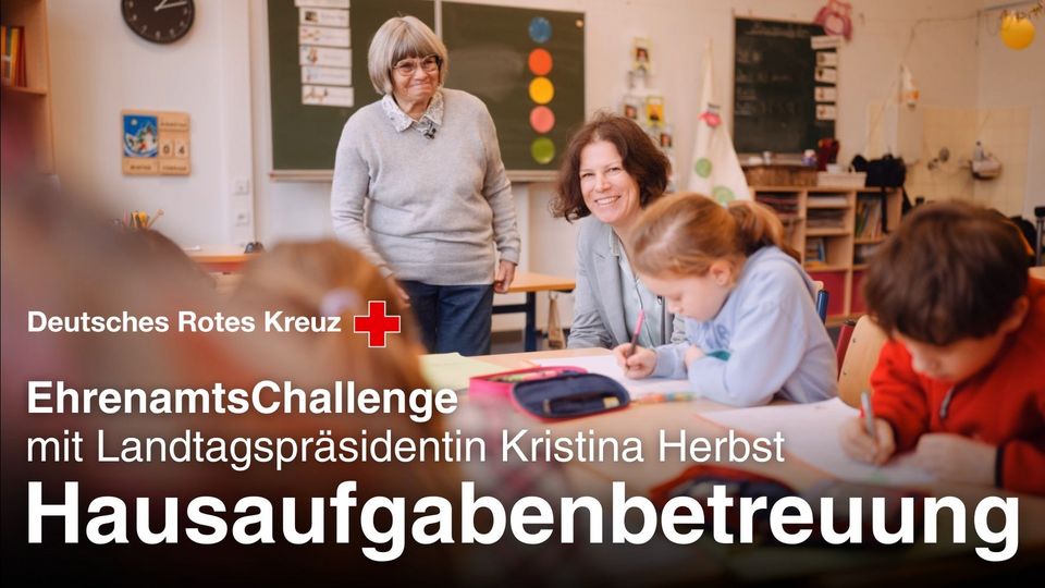 In einem Klassenraum beaufsichtigen 2 Frauen Kinder bei den Hausaufgaben.