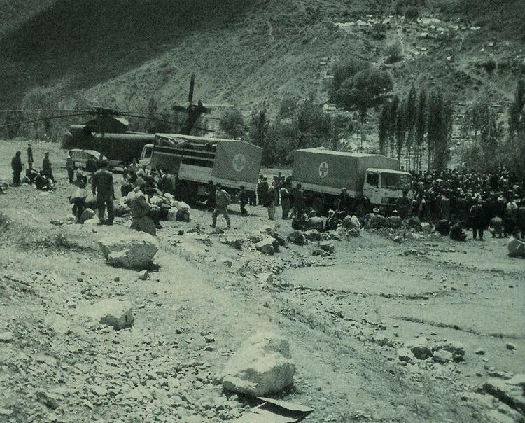 Eine Menschenmenge vor einem Hubschrauber und zwei LKW