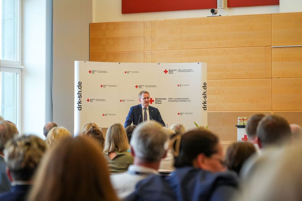 Ein Mann steht an einem Rednerpult und spricht zu großem Publikum.