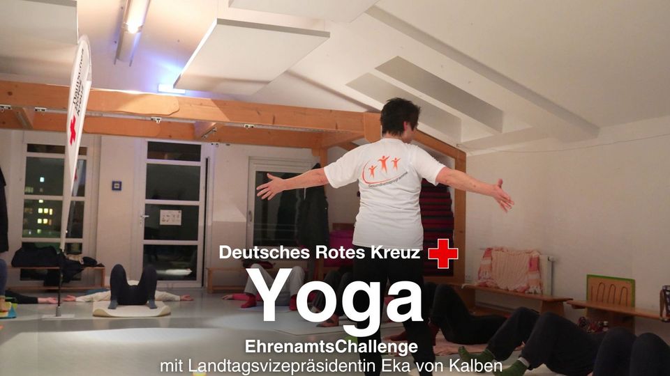 Eine Yoga-Lehrerin läuft durch einen Raum mit Menschen auf Yoga-Matten.