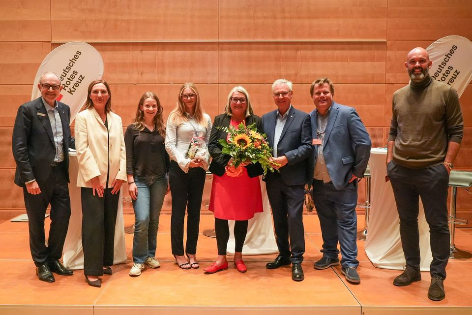 Gruppenfoto aus dem Parlamentarischen Abend des DRK SH Gruppenfoto: Acht Menschen stehen nebeneinander auf einer Bühne.