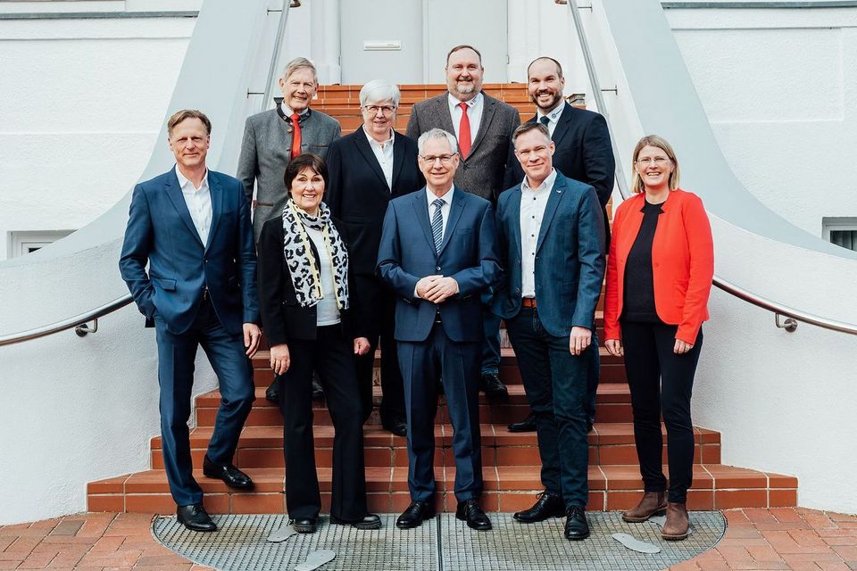 Gruppenbild am Fuße einer roten Treppe vor einem weißen Gebäude