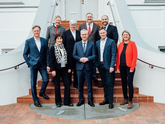 Gruppenbild am Fuße einer roten Treppe vor einem weißen Gebäude