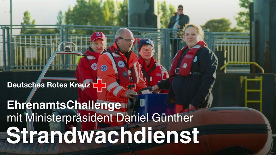 4 Menschen mit roten DRK-Rettungswesten stehen an Bord eines Motorbootes.