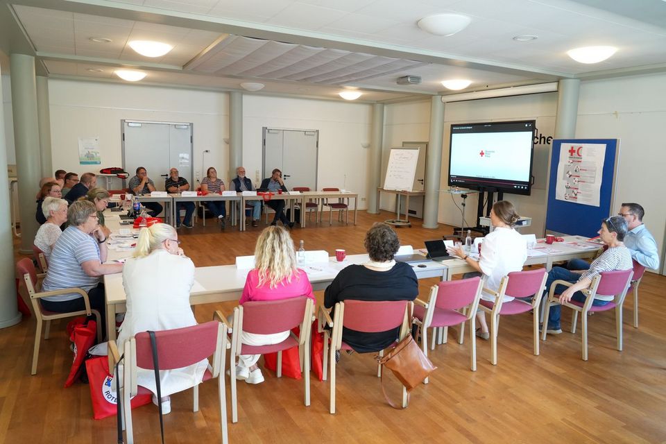 Etwa 20 Personen sitzen in einem Konferenzsaal.