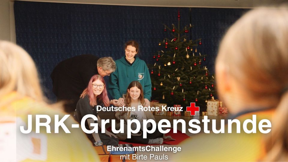 Vor einem Tannenbaum spielt eine Gruppe Jugendlicher mit einer Frau.