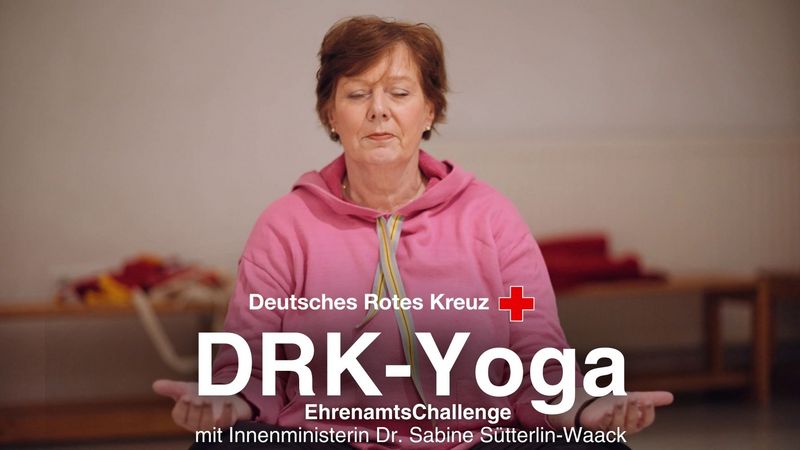 Eine Frau in pinkfarbenem Pulli meditiert im Schneidersitz.