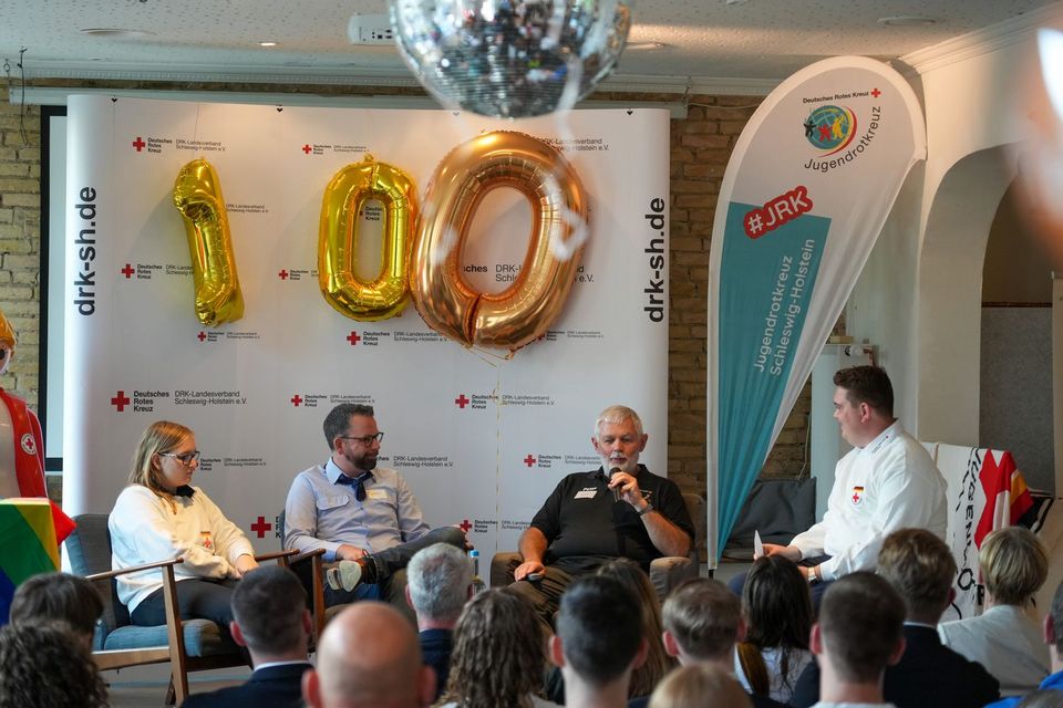 Vier Personen sitzen auf einer Bühne.