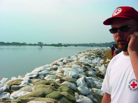 Ein Mann vor der Elbe, die mit Sandsäcken gegen Hochwasser gesichert wurde